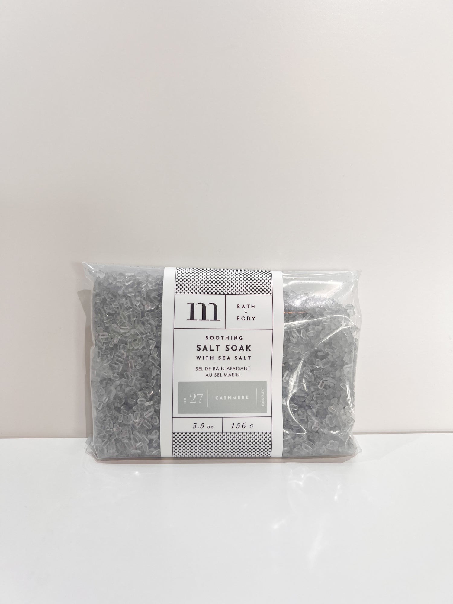 Clear plastic bag of grey bath salt soak with white label featuring text No 27 Cashmere