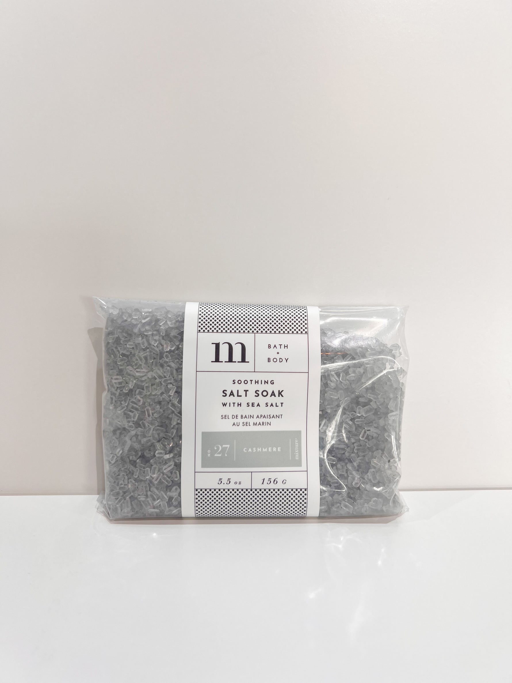 Clear plastic bag of grey bath salt soak with white label featuring text No 27 Cashmere