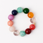 Beaded jewelry bracelet featuring a circular arrangement of polished multi-colored resin spheres on a white background with marbled emerald textures and a translucent bead with a white internal band and a small gold metal accent