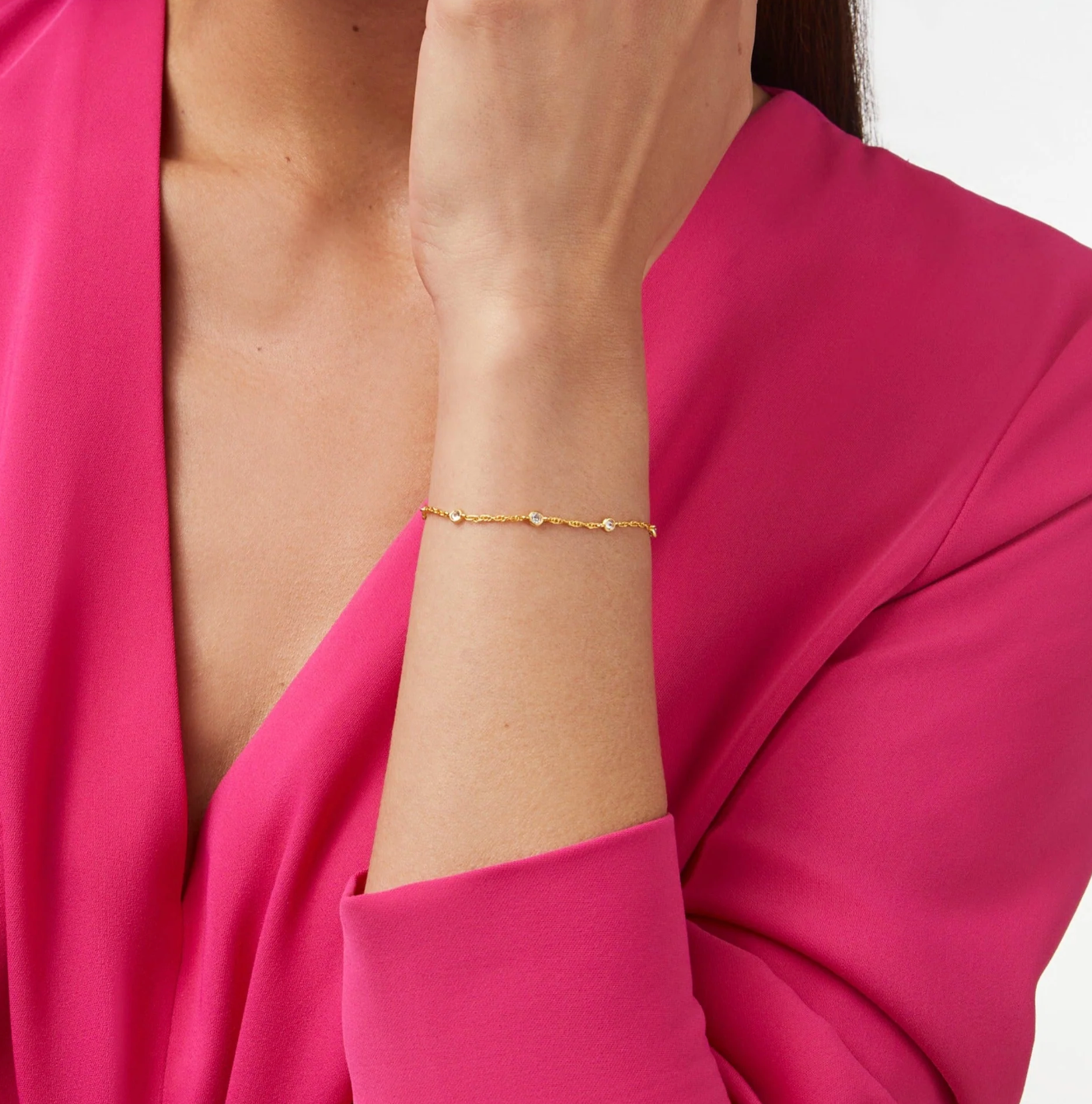 Gold chain bracelet with small embedded clear stones worn on a wrist