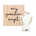 White ceramic angel figurine with gold halo and wing accents beside a light wood plaque inscribed with "my guardian angel" in black script, featuring a small gold heart on the angel's base