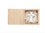 White ceramic cross with gold heart detail inside a wooden gift box with paper filler