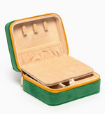 An open green velvet travel jewelry box with a vibrant yellow zipper, revealing a soft beige interior featuring necklace hooks and a removable storage tray for rings and earrings