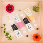 Four tubes of Chez Gagne hand cream arranged on a peach tray with flowers and small white spheres