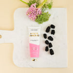 Chez Gagne hand creme tube with blackberries and pink flowers on a marble board