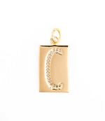 Gold jewelry pendant featuring a rectangular gold plate with a pave-set crystal letter C and a polished circular bail against a white studio background