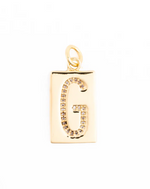 Gold jewelry pendant showcasing a rectangular charm with a pavé-set crystal letter G and a polished metallic gold finish against a white background
