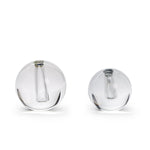 Clear glass, a duo of polished spherical vases in two sizes, each precisely crafted with a narrow internal tube for a single flower stem, against a stark white background