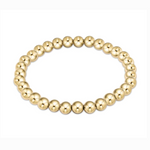 Polished gold beaded bracelet with numerous uniform round beads forming a continuous loop against a stark white background