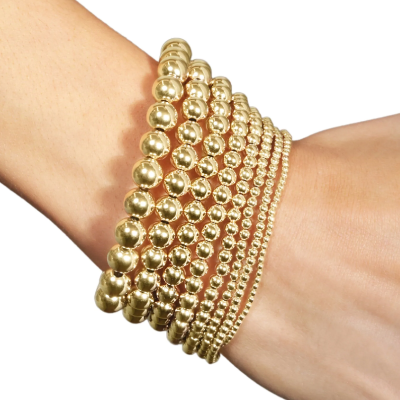 Stack of gold beaded bracelets on a wrist