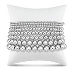 Stack of silver beaded bracelets on a white display pillow