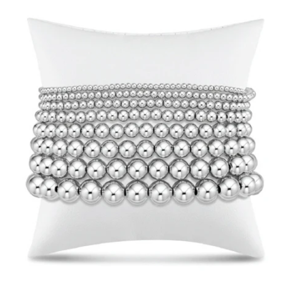 Stack of silver beaded bracelets on a white display pillow