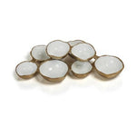 Decorative metal serveware, an organic multi-bowl dish with connected irregular compartments, featuring a smooth white enamel interior and a textured gold finish