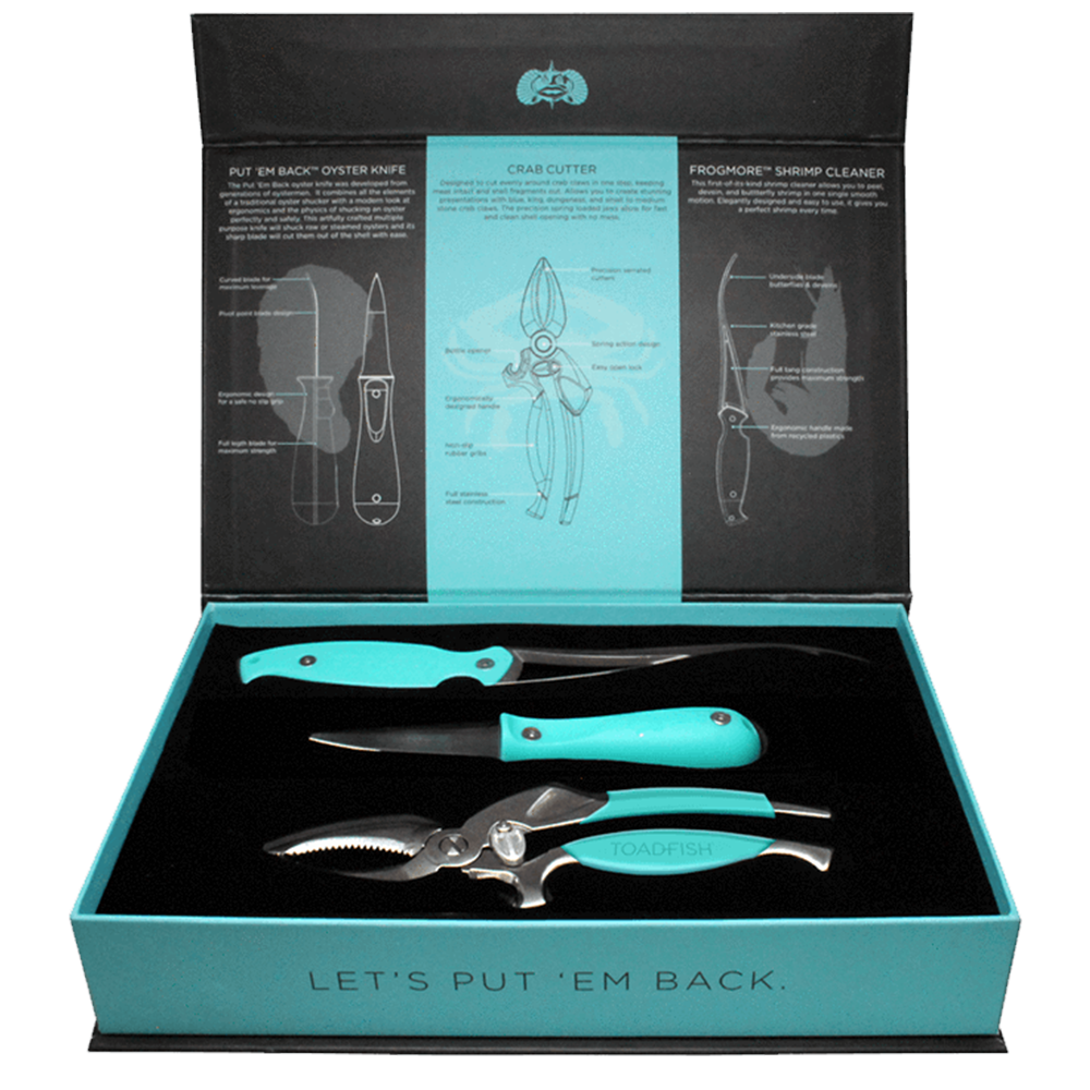 Toadfish product photography of an open black and teal box presenting a three-piece seafood toolset with vibrant teal handles including an oyster knife, shrimp cleaner, and crab cutter, resting on a black velvet insert, with the lid featuring illustrative diagrams and the box front declaring "LET'S PUT 'EM BACK"