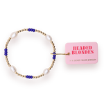 14K gold filled beaded bracelet by Beaded Blondes featuring white oval freshwater pearls and cobalt blue accents attached to a pink rectangular brand tag