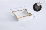 White porcelain square bowl by Pampa Bay featuring a gold beaded rim and wavy organic edges against a white background with 7x7x2 inch dimension lines and a black Pampa Bay brand seal