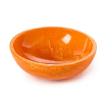 A vibrant orange resin bowl with a glossy finish and mottled interior texture isolated on a white studio background