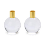 Clear glass and brass candle holders featuring two minimalist spherical transparent globes with polished gold-tone cylindrical tops on a clean white background