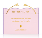 Product photography Lucky Feather gold butterfly bangle bracelet resting on a pink wavy-edged display card featuring Flutter and Fly text and a small golden bead charm
