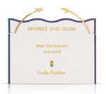 Lucky Feather gold-plated cuff bracelet featuring a star charm and a crescent moon charm displayed on a white and blue product card with Sparkle and Glow text