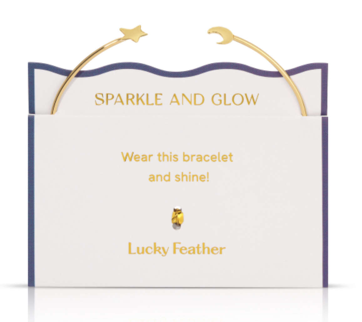 Lucky Feather gold-plated cuff bracelet featuring a star charm and a crescent moon charm displayed on a white and blue product card with Sparkle and Glow text