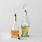 Two glass bottles with crystal stoppers and one loose crystal stopper on a white surface