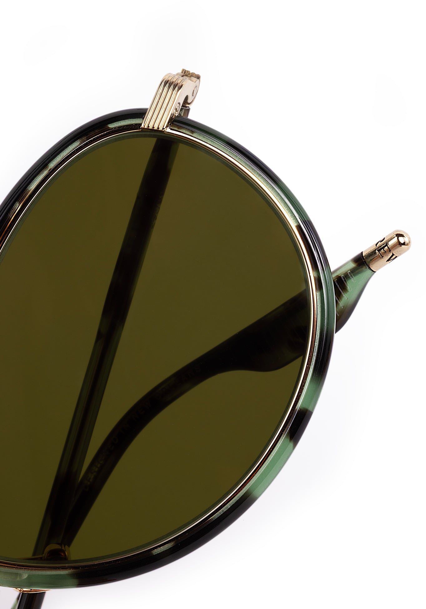 Close-up of round dark green lens sunglasses with a green tortoiseshell frame, featuring an ornate gold volute hinge and "DESIGNED IN NEW ORLEANS" inscribed on the inner temple