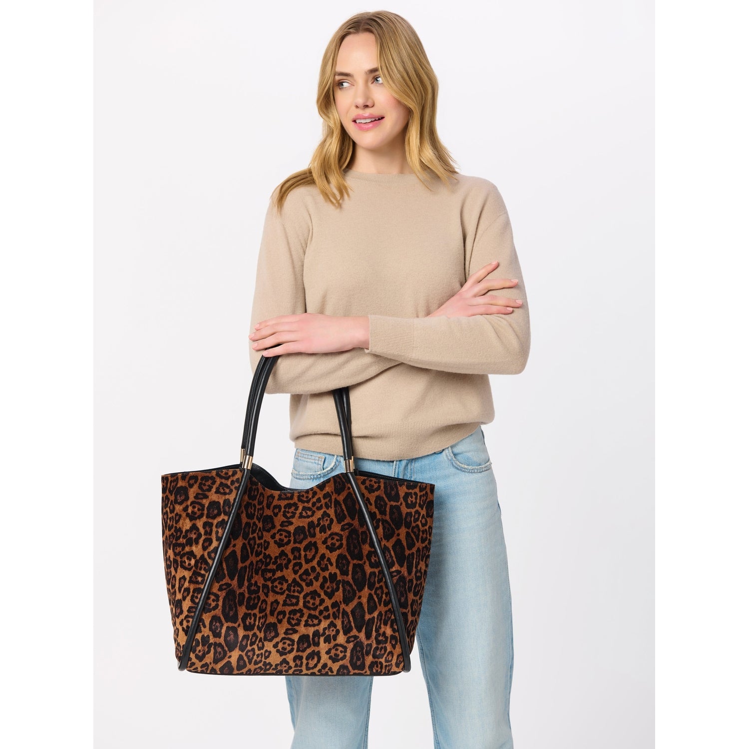 Woman holding a large leopard print tote bag with black leather handles