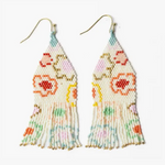 Beaded earrings featuring a cream-colored base with a colorful floral pattern in red, orange, and light pink, delicate gold bead accents, and long pastel fringe in shades of blue, green, and pink