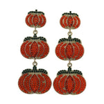 Decorative jewelry earrings featuring a pair of dangling pumpkin-shaped designs with glittering red and green rhinestones on gold-toned metal