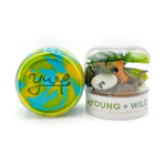 Two Young + Wild and Friedman play kits on a white background, one with vibrant swirled blue, green, and yellow sensory dough featuring the 'ywf' logo, and the other a clear container filled with miniature dinosaur toys including an orange T-Rex, a grey long-neck dinosaur, a white egg with a dino silhouette, and green foliage