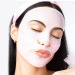 Photography of a woman with closed eyes wearing a light pink sheet face mask and a pink headband featuring a gold hoop earring