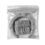 Product photograph by LEMON LAVENDER of a grey three-piece super soft dryband set featuring a puffy headband and two scrunchie wristbands, sealed in clear plastic packaging with the slogan 'i washed up like this'