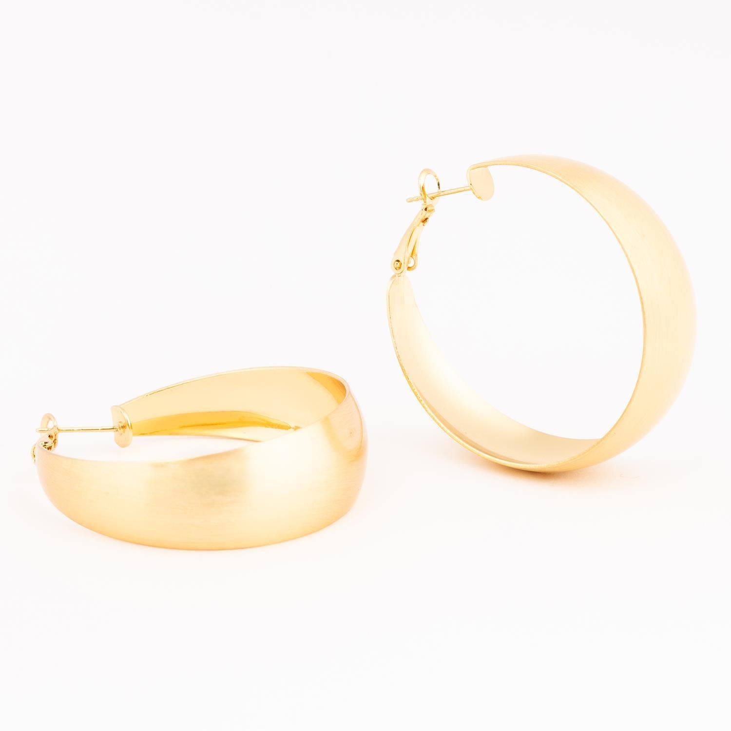A pair of wide chunky gold-toned hoop earrings with a brushed matte finish and a visible post-back closure