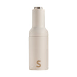 Off-white minimalist salt and pepper grinder with a silver top and a gold S logo on the lower body
