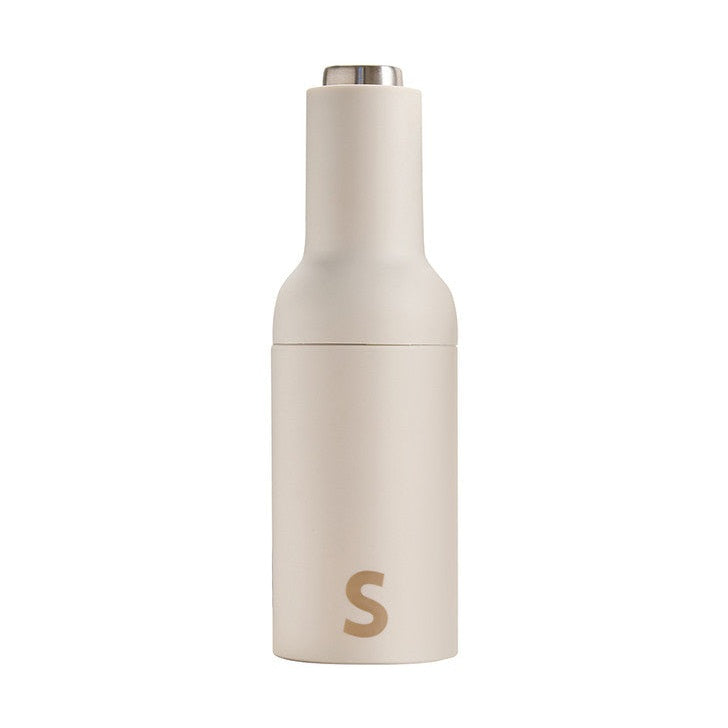 Off-white minimalist salt and pepper grinder with a silver top and a gold S logo on the lower body
