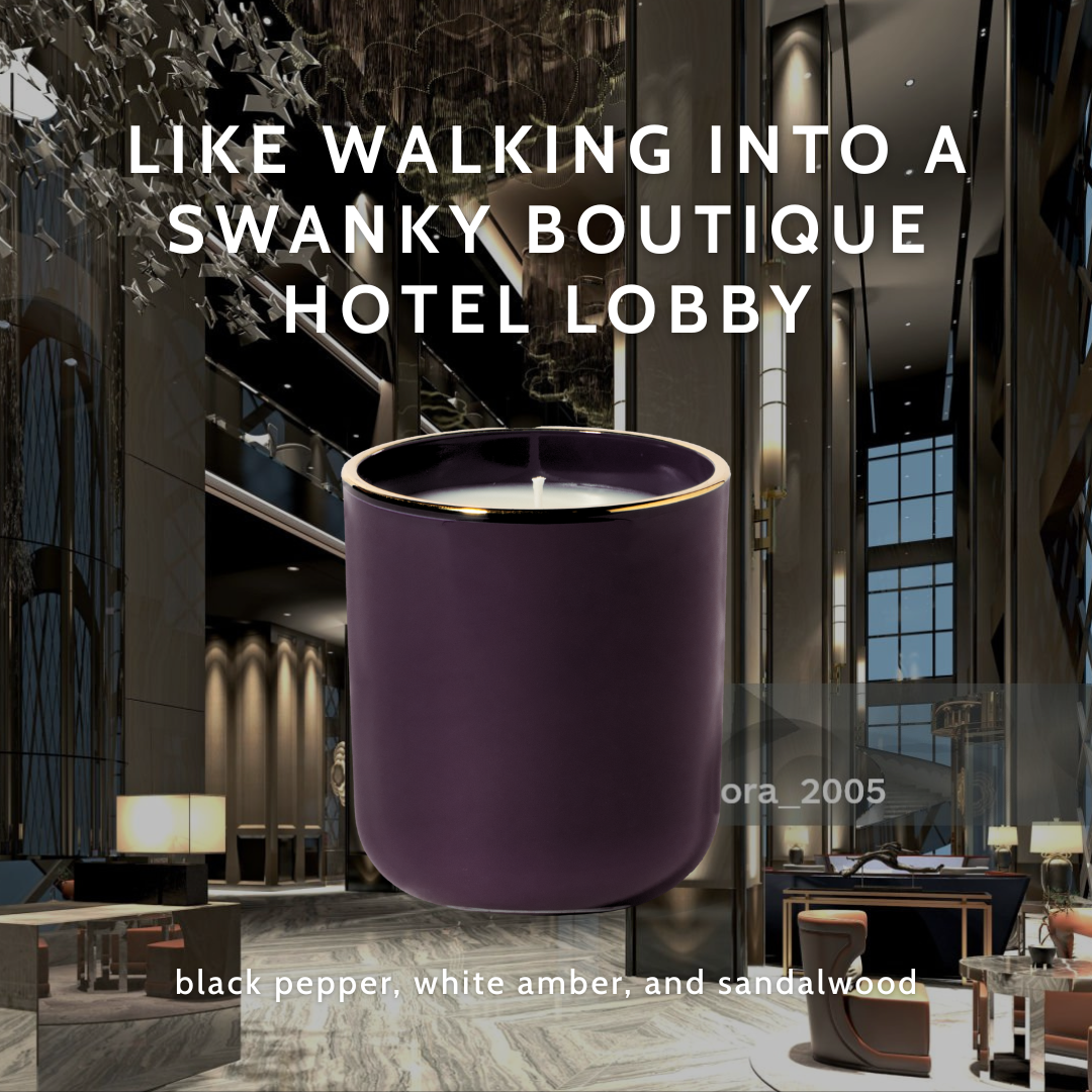 Dark purple candle with gold rim against a luxury hotel lobby background