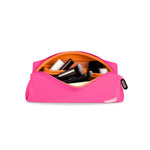 A hot pink Kusshi makeup bag with a bright orange interior filled with several black makeup brushes and other cosmetic items on a white background