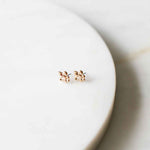 Two small rose gold floral stud earrings with tiny clear stones centered on a clean white marble surface