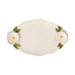 Cream-colored ceramic oval serving platter featuring raised white magnolia flowers with yellow centers and green leaves on each end and a delicate scalloped beaded rim
