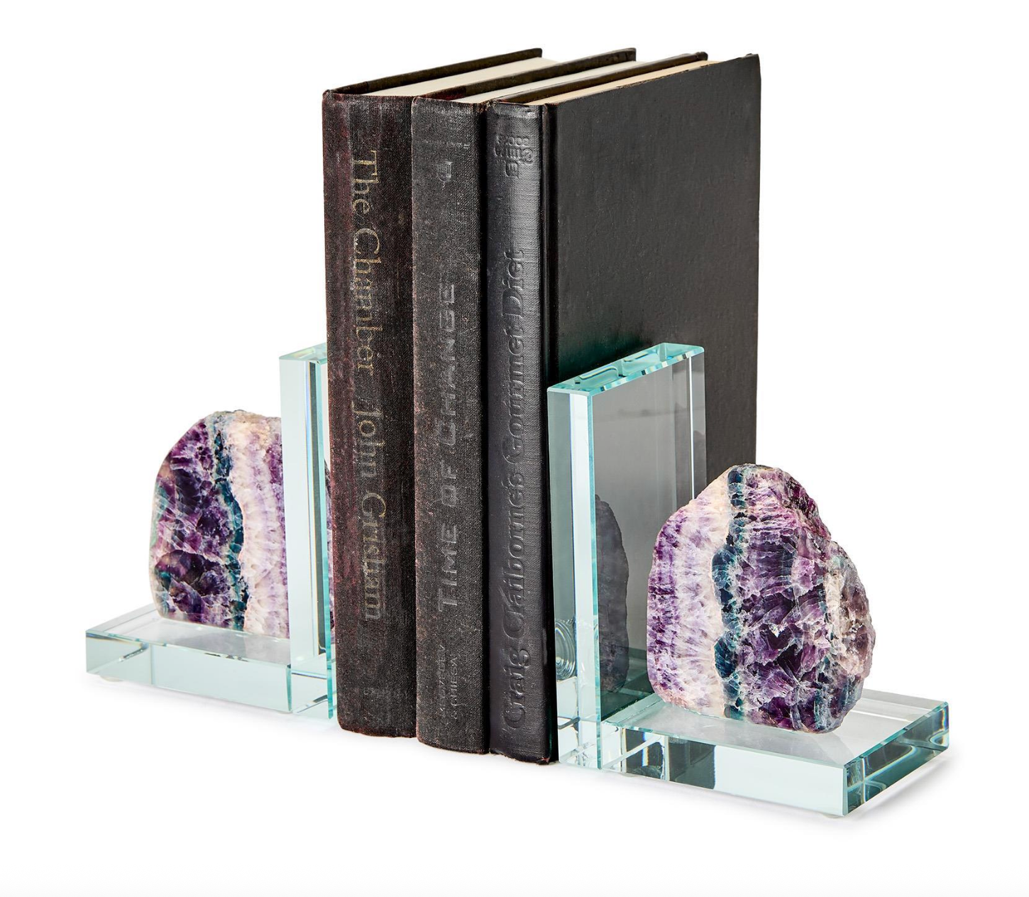 Glass and fluorite crystal bookends holding three vintage books against a white background featuring raw-edged stones with vibrant purple and teal banding and thick transparent L-shaped supports showcasing weathered book spines titled The Chamber and Time of Change
