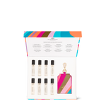 Product photography by Glasshouse Fragrances, a luxury fragrance discovery set featuring eight miniature travel perfumes with names like Forever Florence and Midnight in Milan, presented in an in an open white box with a vibrant multi-colored striped lid and a matching keyring holder with gold hardware