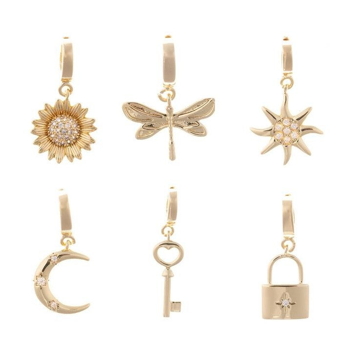 Gold hoop earrings featuring six distinct golden charms arranged on a white background: a sparkling sunflower, a delicate dragonfly, a dazzling sun with clear gems, a crescent moon adorned with stars, a heart-shaped key, and a padlock with a central starburst gemstone