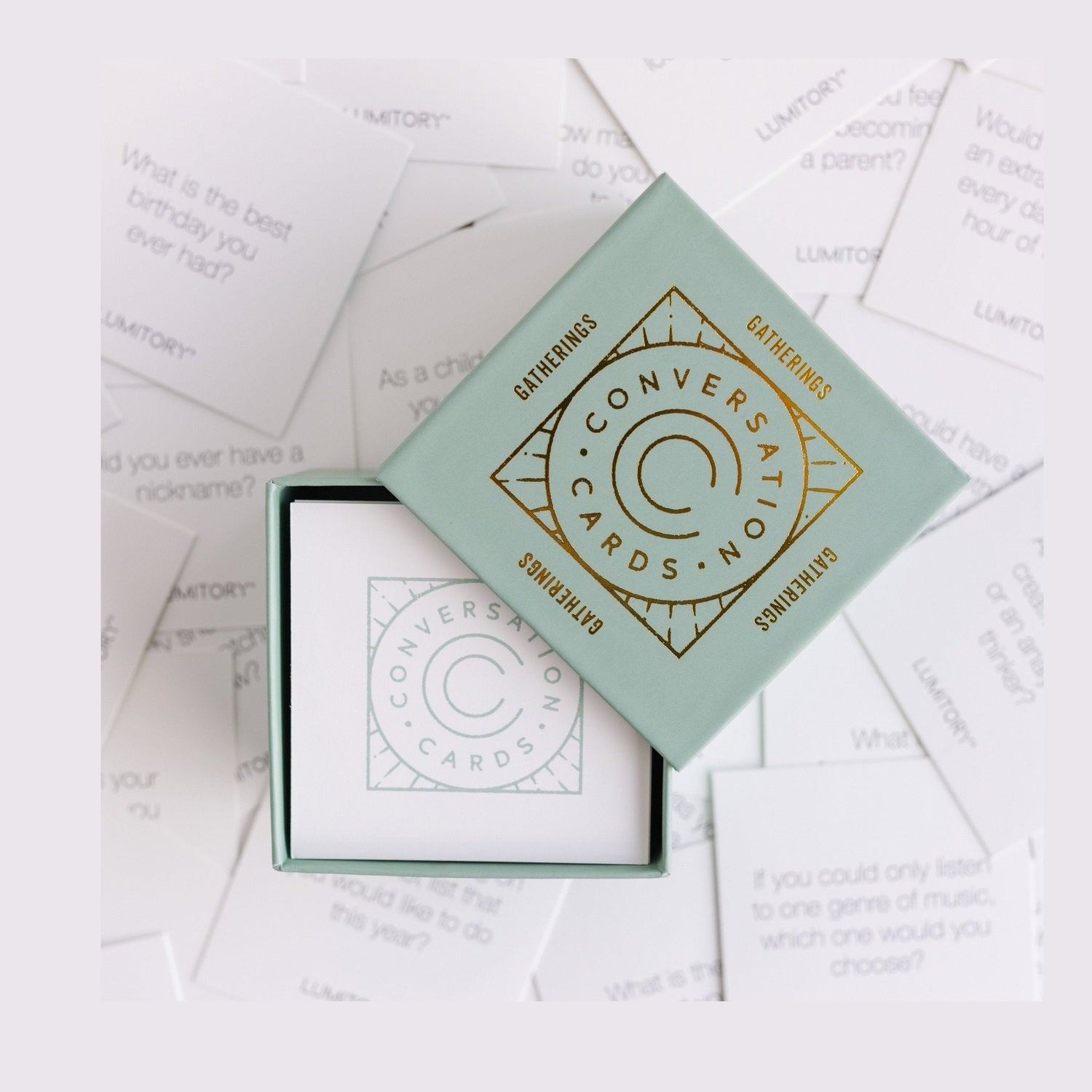 Open box of Gatherings conversation cards surrounded by individual prompt cards