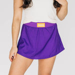 Person wearing a purple athletic skirt with a Geaux Tigers waistband label