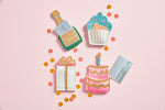 Felt gift card holders shaped like a champagne bottle, cupcake, gift box, and cake on a pink background with confetti