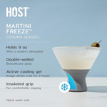 Product photography by HOST of a frosted Martini Freeze Cooling Glass with a grey insulated grip, containing a martini garnished with a green olive, on a light blue background featuring a blue snowflake graphic