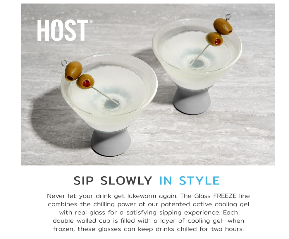 Product photography by HOST® featuring two frosted martini glasses with grey bases on a light grey textured surface, each garnished with two green olives with red pimentos on a silver pick