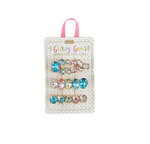 Product photography of a set of Glitzy Gems rhinestone hair clips on a polka-dotted card, featuring three rows of iridescent blue pink and clear oval stones in gold-tone settings with a pink ribbon hanger