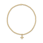 Polished gold beaded stretch bracelet adorned with a delicate four-ball cross charm